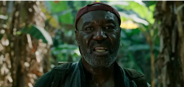 Paul stands in the jungle. He's an aging Black man wearing a backwards baseball cap.
