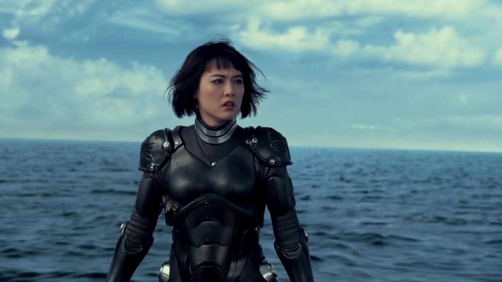 Mako Mori (Rinko Kikuchi) stands on a raft in the middle of the ocean, wearing futuristic armor