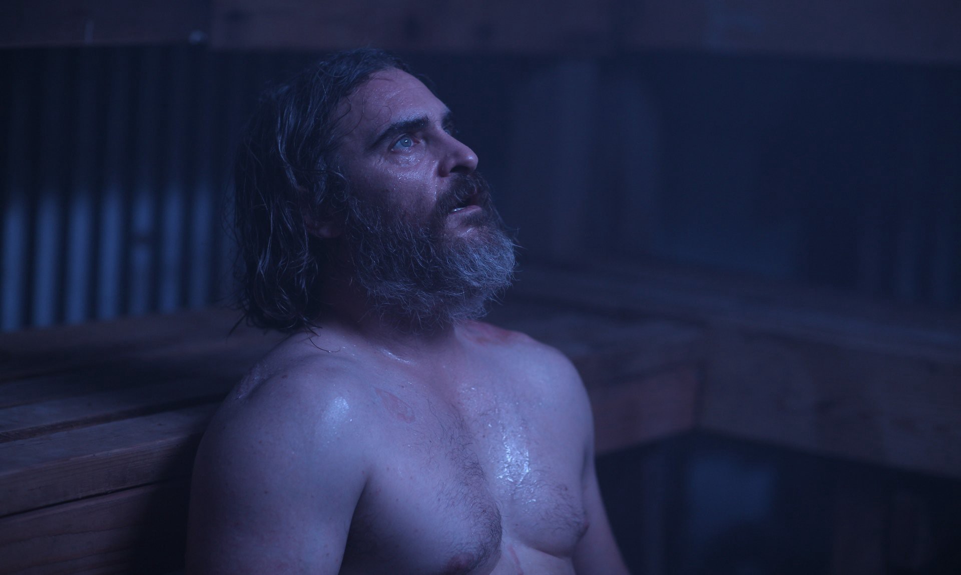 Joe (Joaquin Phoenix) sits in a sauna, shirtless and sweaty.