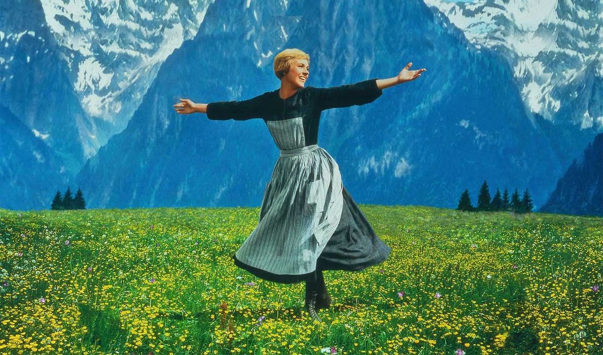 Maria (Julie Andrews) spins in a field in front of the Alps
