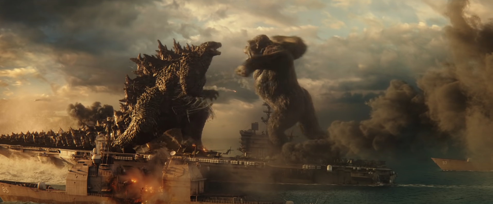 Godzilla and Kong face off on the back of an aircraft carrier. Kong is about to punch Godzilla in the face.