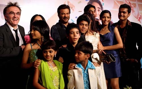 The cast of Slumdog Millionaire (who are all Indian) posing on the red carpet with the film's director Danny Boyle (who is white).