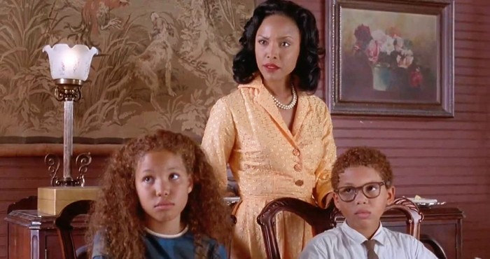 Roz (Lynn Whitfield) stands behind her children, Eve and Poe (Jurnee Smollett and Jake Smollett). All are Black and dressed in 1960's period attire.