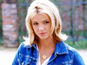 Still of Britney Spears as Lucy in "Crossroads". She is wearing a gold necklace and blue jean jacket.