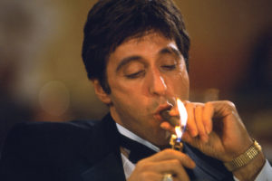 Al Pacino lights and smokes a cigar.