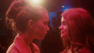 Anne and Sasha stare at one another in a club setting with pink lighting