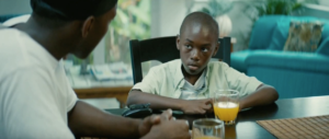 A young boy is sitting at the table quietly drinking juice.