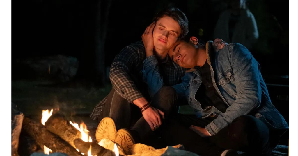 A still of Victor and Benji sitting together at a campfire