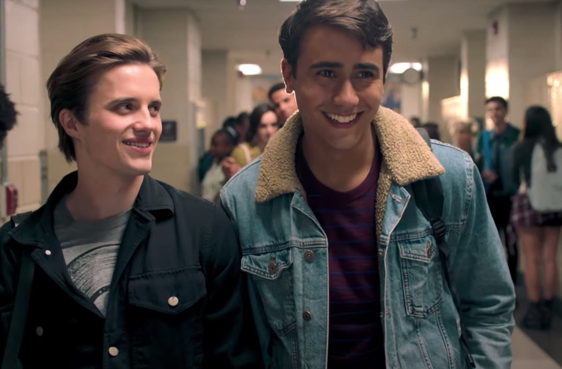 A still of Victor and Benji smiling as they walk through the school hallways