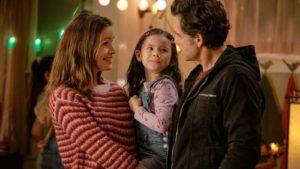 Still from "Yes Day". Allison holds her daughter while speaking to Carlos.