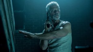 A still from "Don't Breathe" of Nordstrom with a gun in the dark