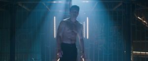 A still from 'Shang-Chi' of shirtless Simu Liu as Shang-Chi emerging from the shadows in the fighting ring