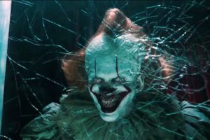 Pennywise smiles deviously, spider webs around his face.