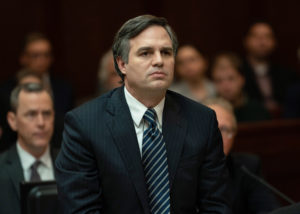 Mark Ruffalo in "Dark Waters". He is standing in what appears to be a courtroom with people sitting behind him.