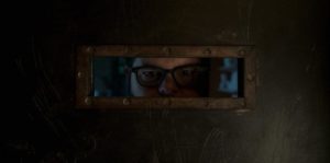 Gary peeks through slat in door, still from 'Wolf Like Me'