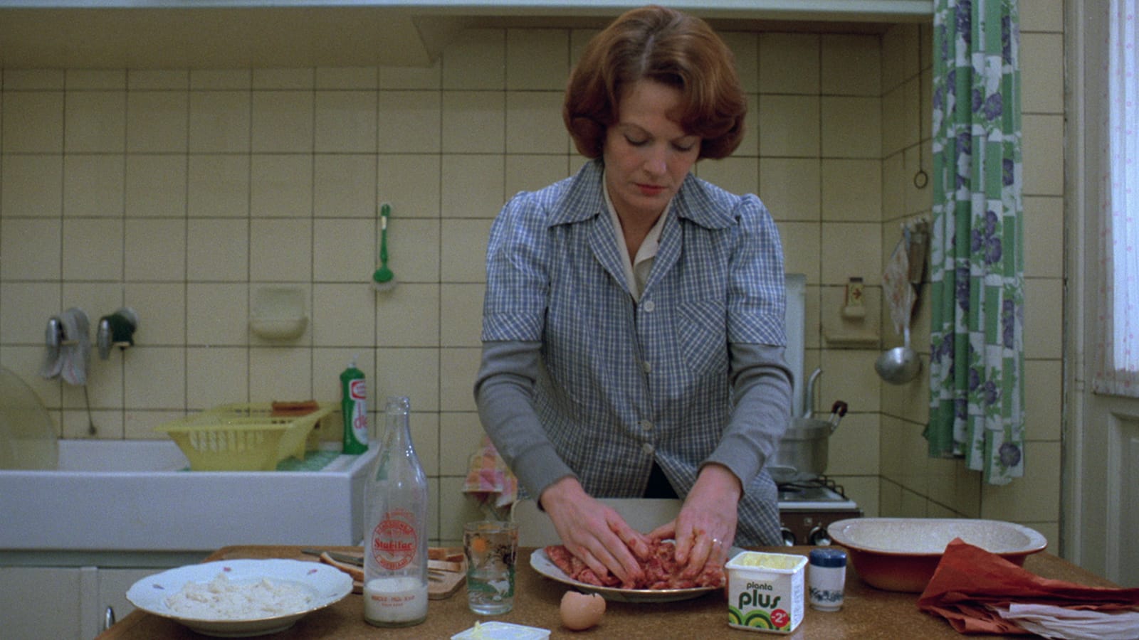Jeanne Dielman in kitchen, folding meat