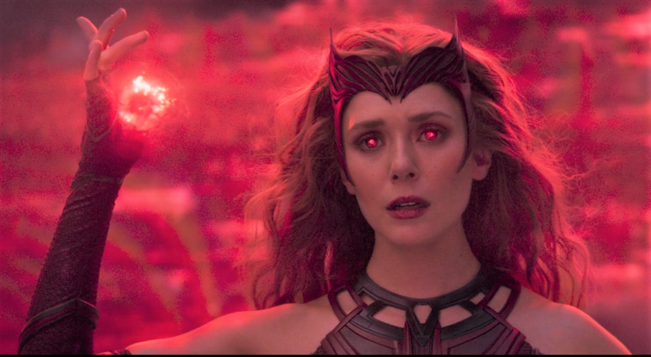 A still from WandaVision of the Scarlet Witch surrounded by red magic and holding a blast of red energy