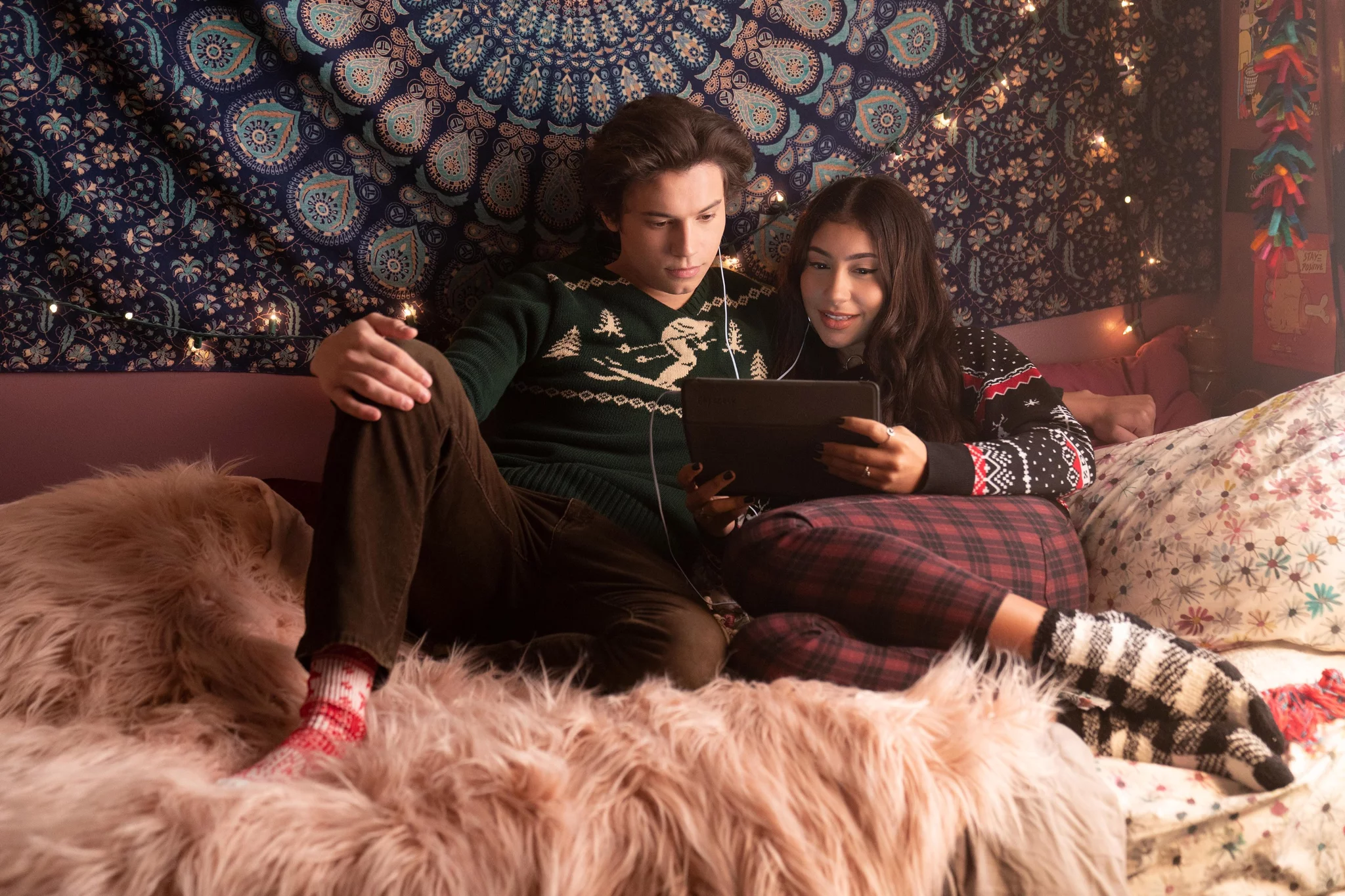 A still from Love, Victor of Felix and Pilar on her bed watching a movie on an iPad together