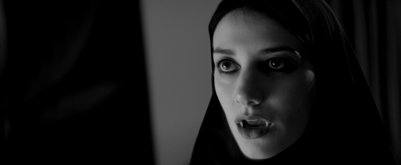 We see close-up of The Girl wearing a black chador, and her fangs piercing out.