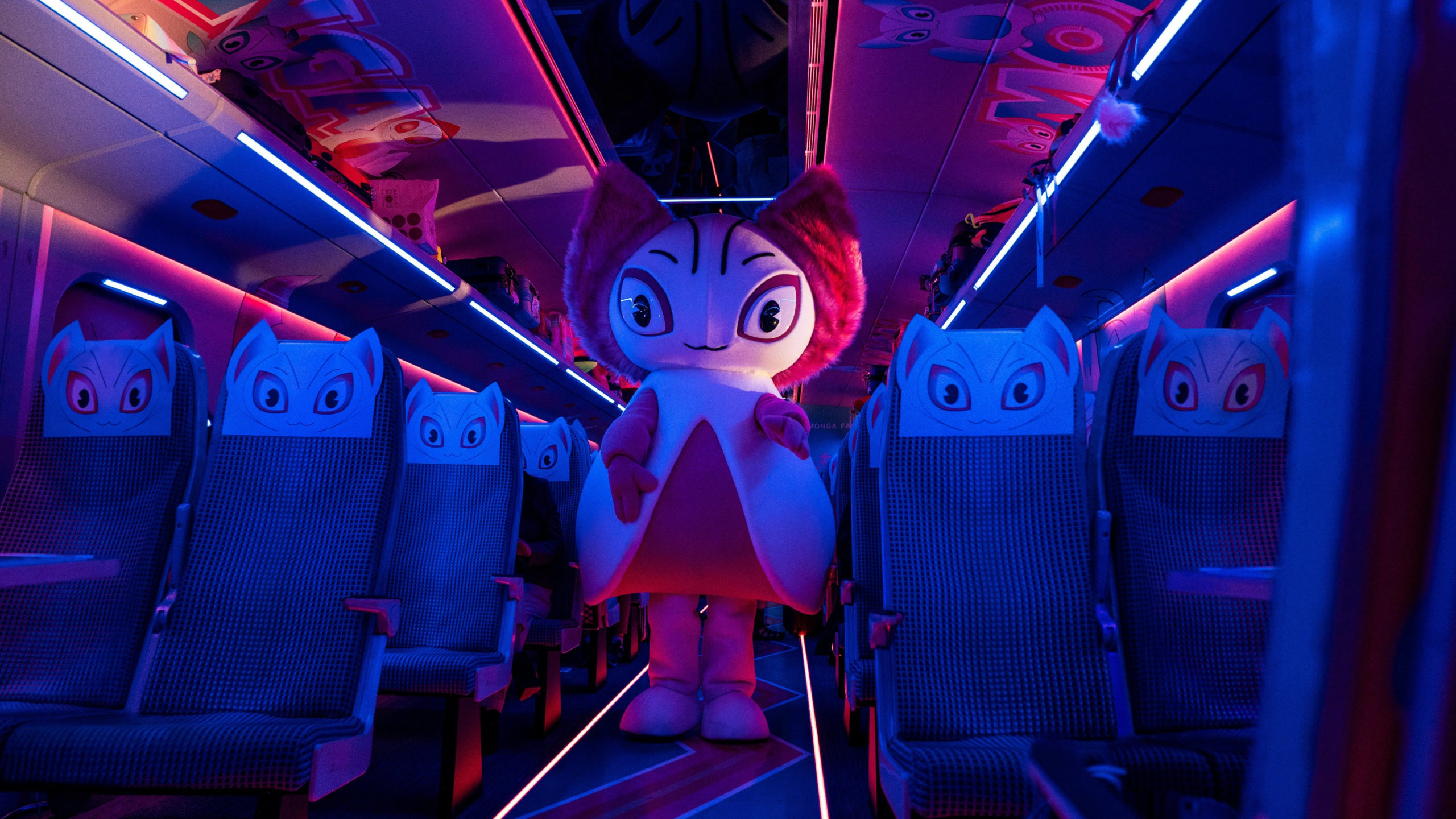 An image from Bullet Train of someone in a costume of an animated pink character surrounded by seats in matching covers on the train