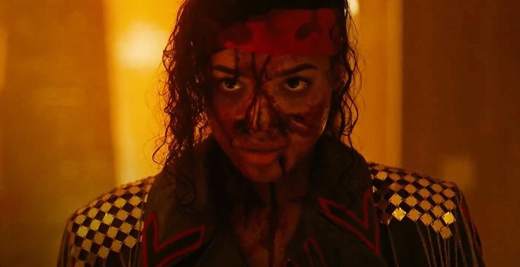 Cherie's face is covered in blood. Her hair is held back, she's wearing a head band, the blood on her face looks like battle marks
