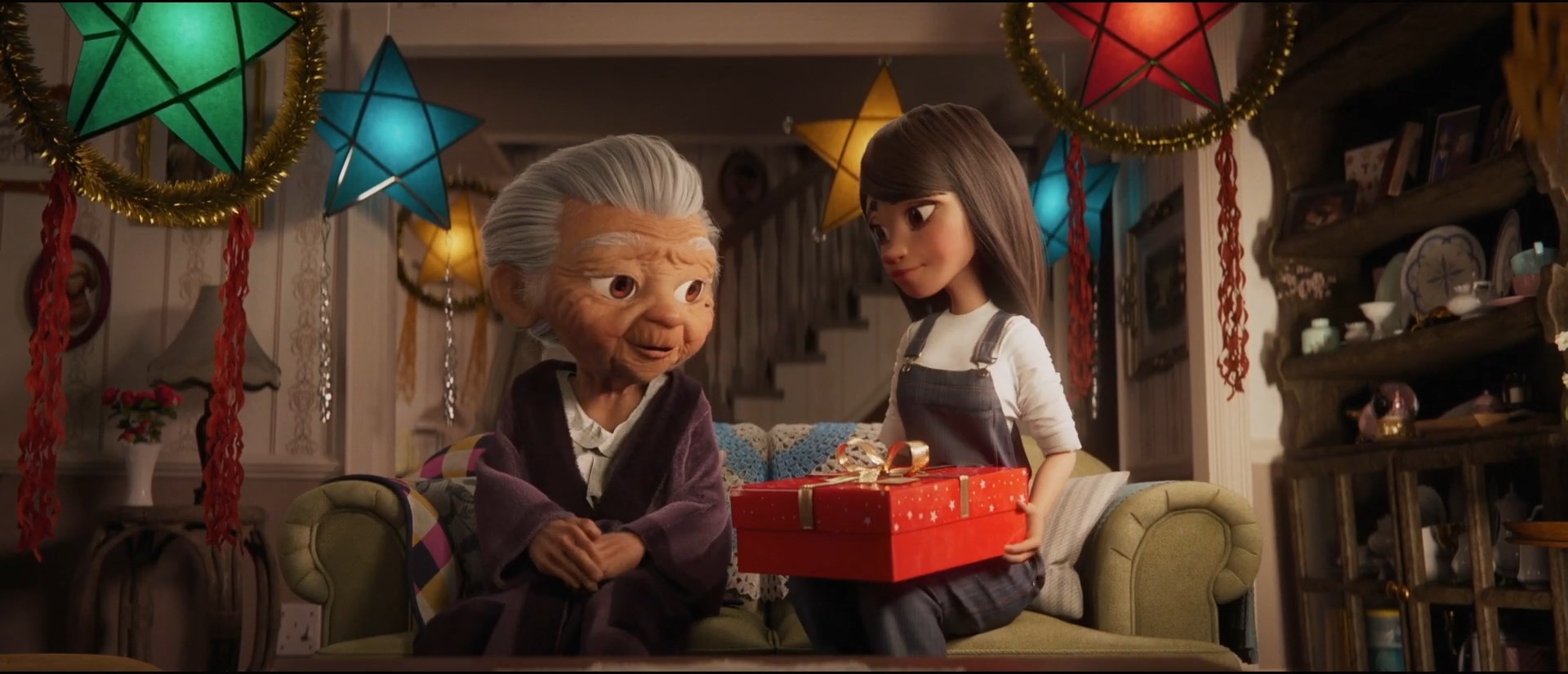 The grandmother and granddaughter sitting next to each other. Surrounded by star paper lanterns, granddaughter holding a present