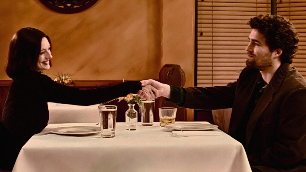 Ashley and Peter shake hands at the dinner table of their date